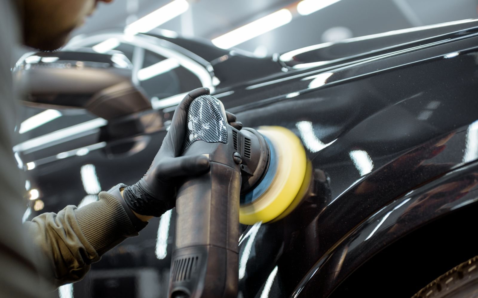Lakcorrectie met een polijstmachine op een donkere auto